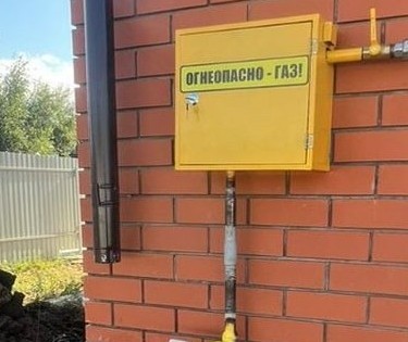 Подключённый газовый счетчик на стене кирпичного дома.
